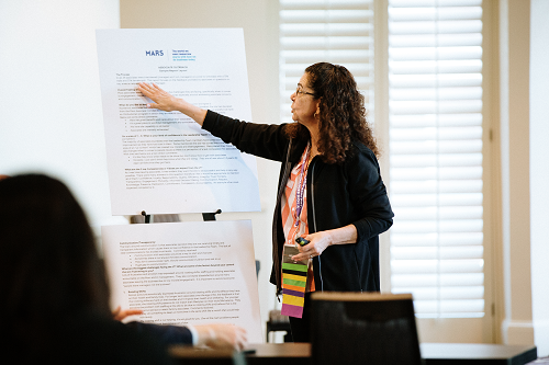 Photo of Presenter Pointing to a Bulletin Board